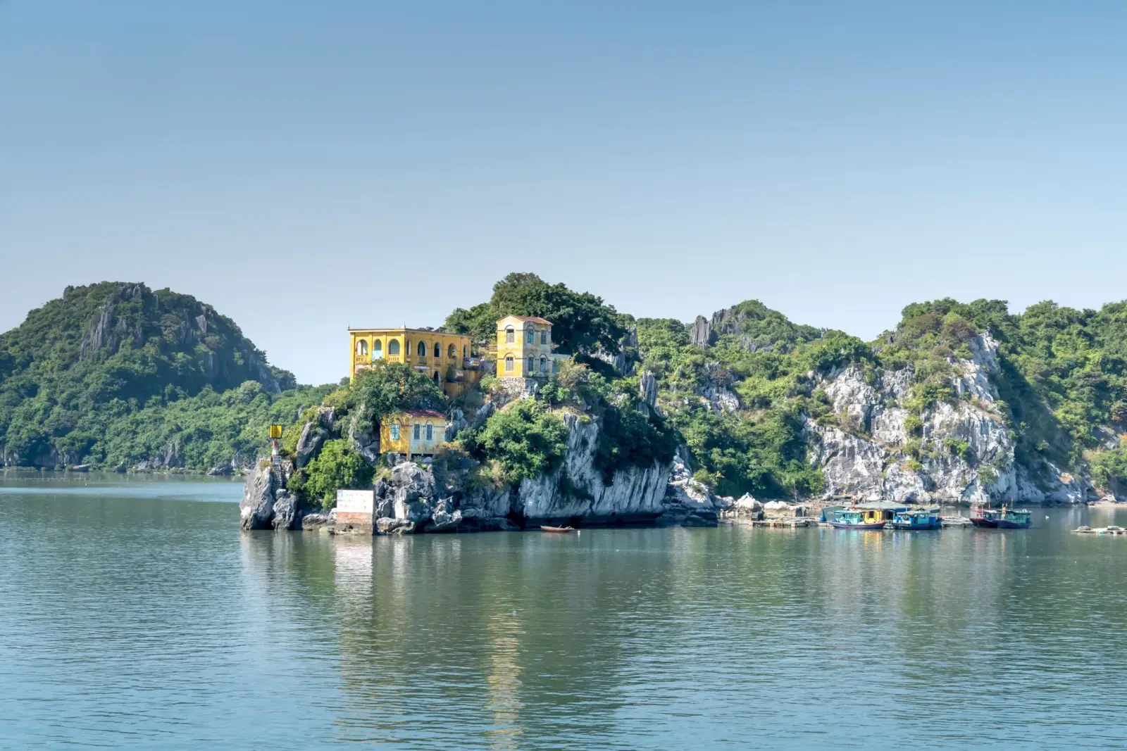 Yellow colonial house perched on a cliff over Lan Ha Bay, Cat Ba