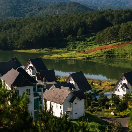 A-frame chalet villas beside a calm lake surrounded by pine forest in Da Lat