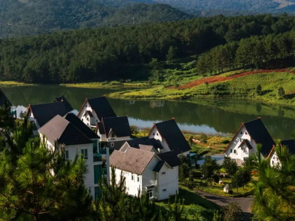 A-frame chalet villas beside a calm lake surrounded by pine forest in Da Lat