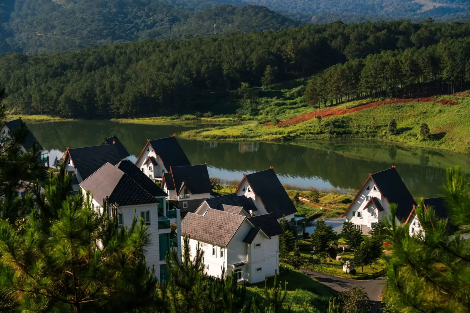 A-frame chalet villas beside a calm lake surrounded by pine forest in Da Lat