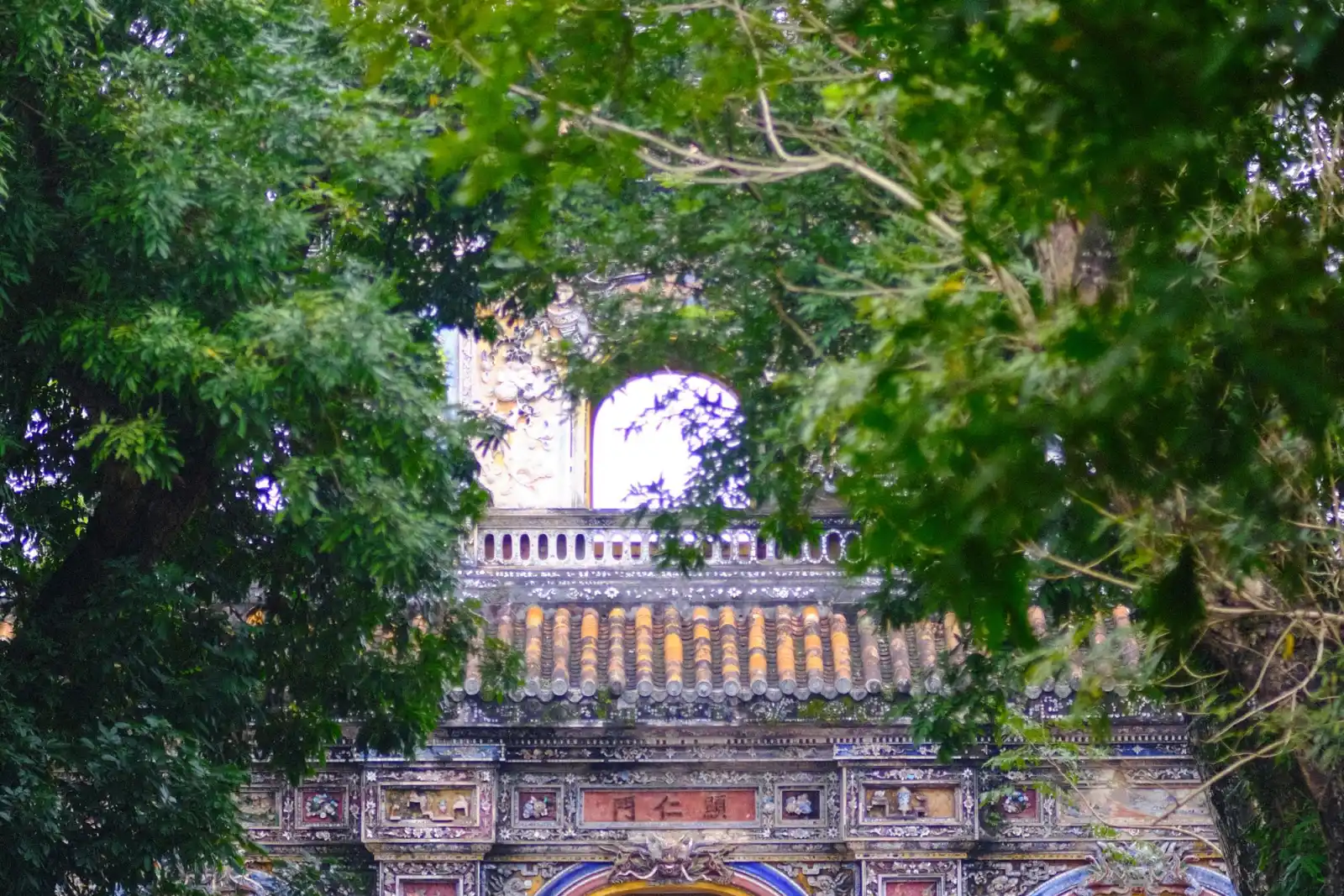 Historic gate framed by trees in Hue