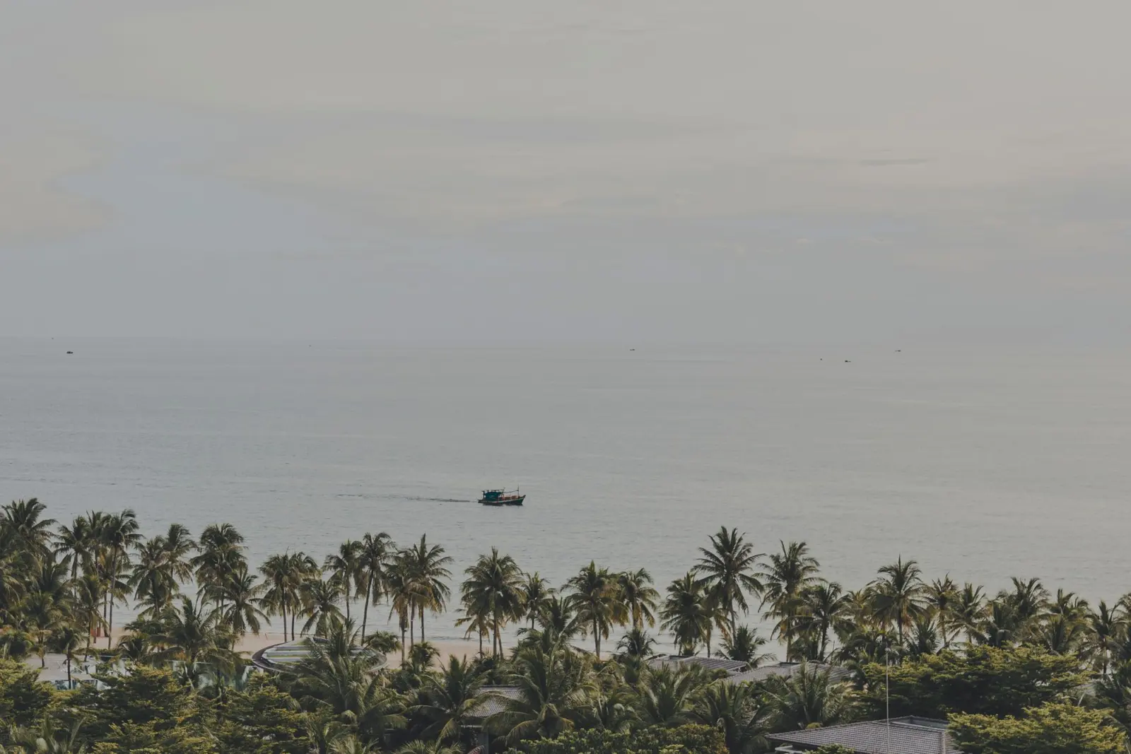 Palm-lined beach with a boat on the calm sea in Phu Quoc