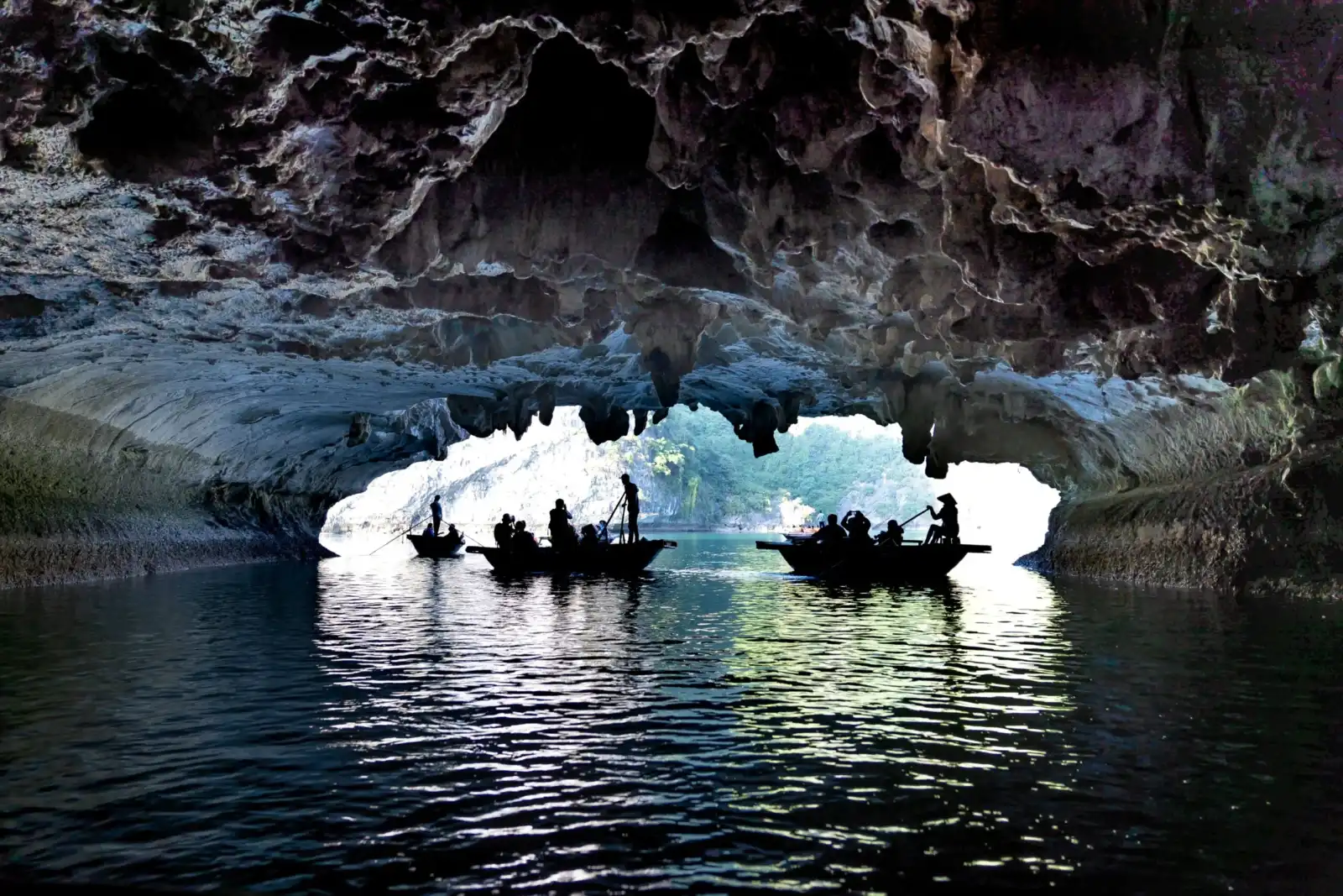 Silhouetted boats carrying visitors through a limestone cave in Phong Nha-Ke Bang