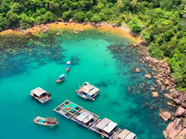 Floating fish farms and boats in a turquoise cove on Phu Quoc island
