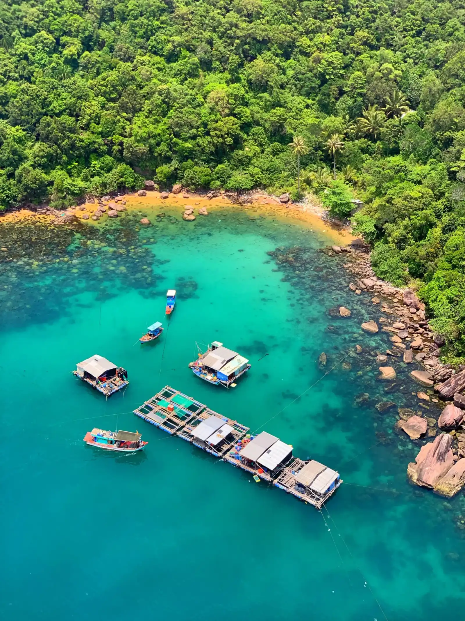 Floating fish farms and boats in a turquoise cove on Phu Quoc island