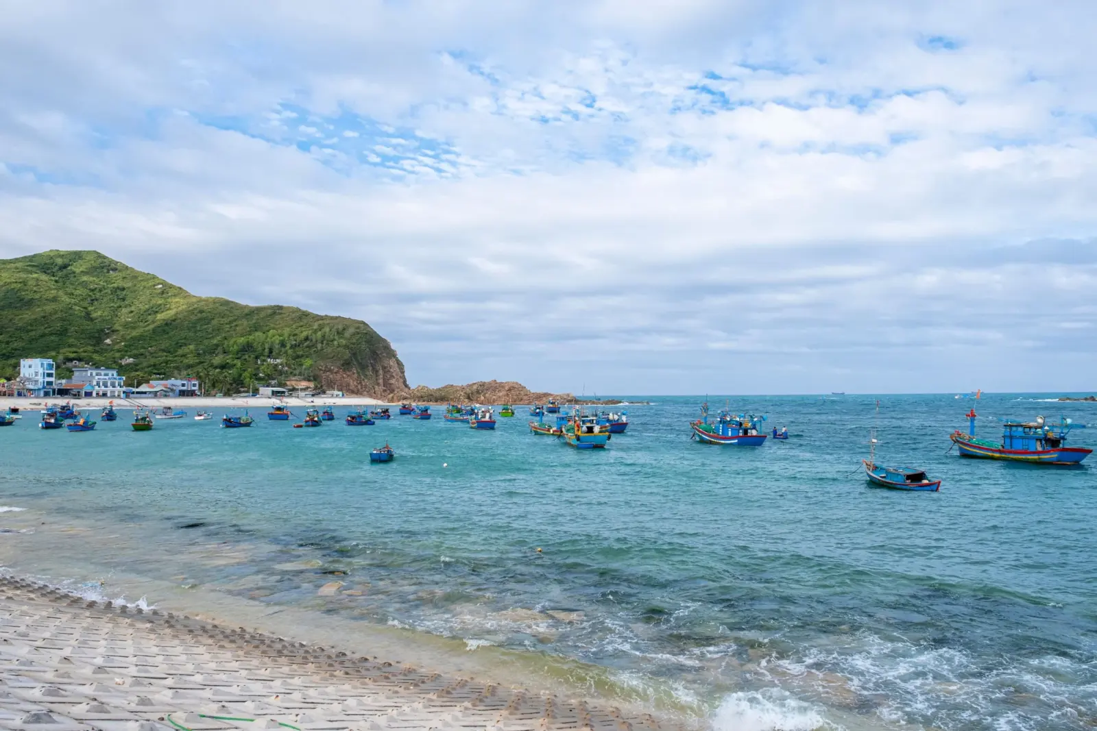 Colorful fishing boats moored near a rocky headland in Quy Nhon
